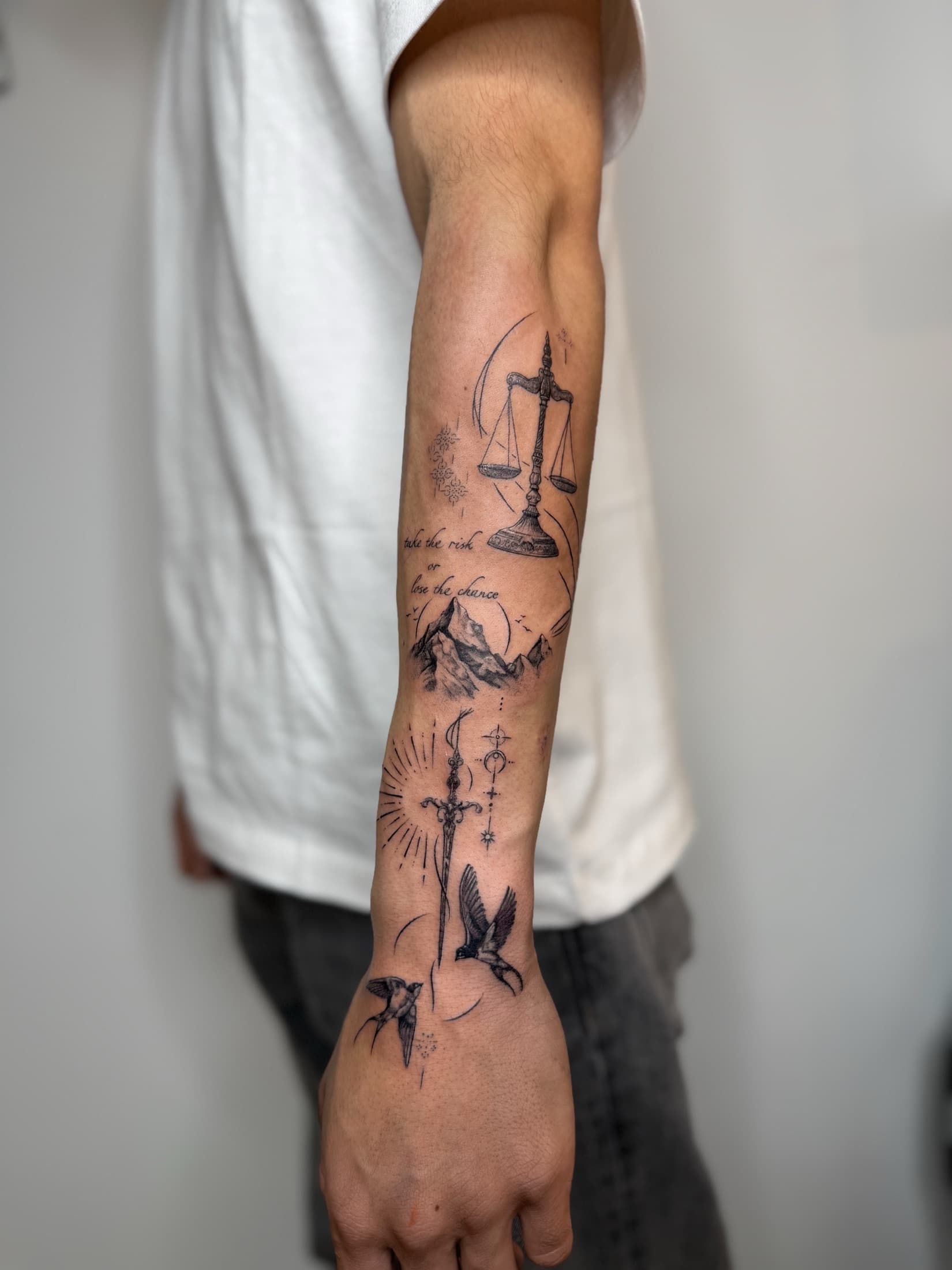 Forearm composition with scales, mountains, a sword and birds